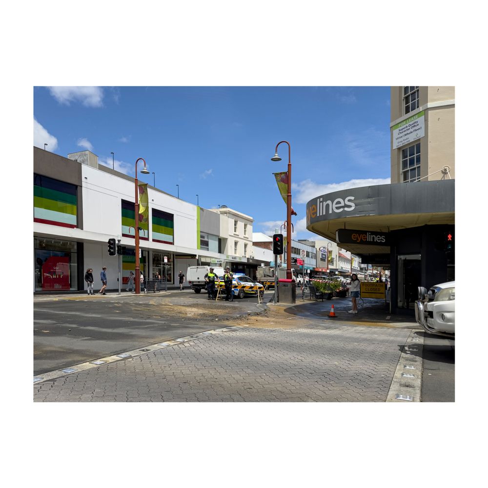 A street corner showing part of the road flooded and roadworks happening
