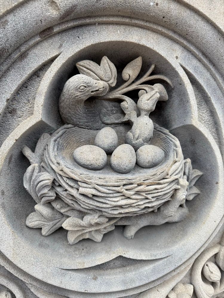 Unsettlingly realistic hatchling carved in limestone on a pillar in Central Park. Four unhatched eggs surround the emerging baby bird, who is not cute. Its mother is depicted in the background looking prouder than she should. 