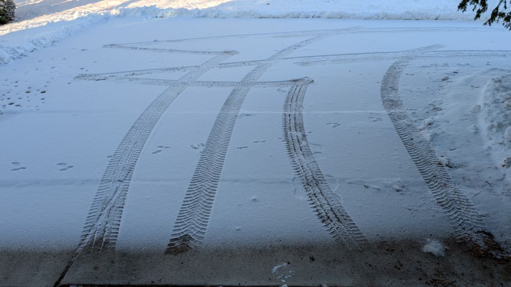 薄く積もった雪にタイヤの切り返し痕がついている
