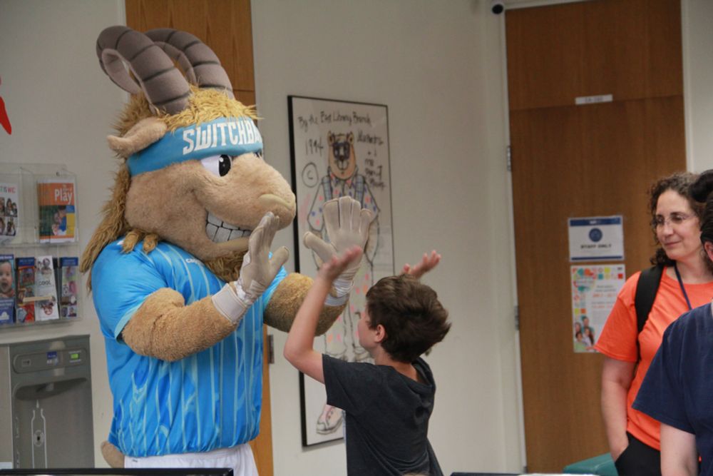Ziggy high-fives with a kid inside of the Library. 