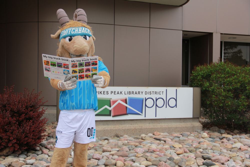 Switchbacks mascot Ziggy, who is a mountain goat, reads a book at the Library. 