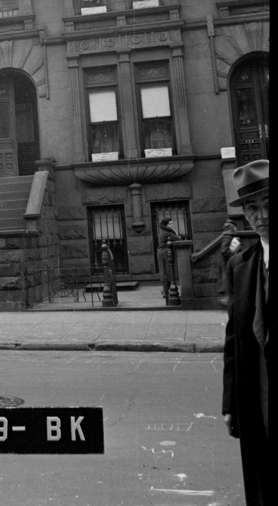 slick-looking young man in hat and fine suit photobombs the surveyor, leaning in on the right like Chris Hansen