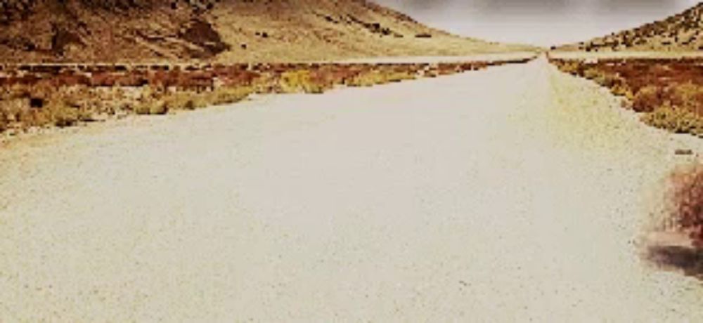 a dirt road going through a desert landscape with mountains in the background