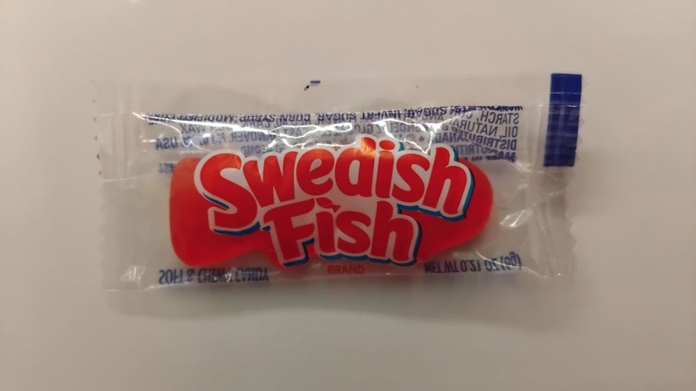 A single Swedish Fish in its plastic wrapper