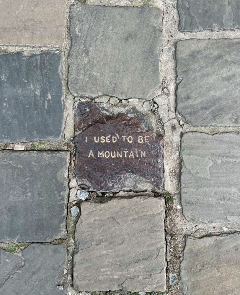 Photo from Brussels of cobblestones. One is carved with the words: I used to be a mountain