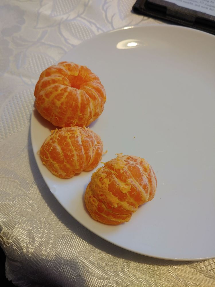 Weißer Teller mit zwei geschälten Mandarinen.