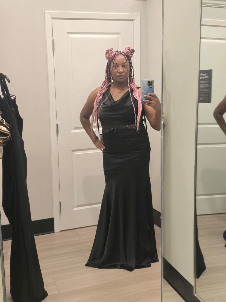 Pink haired baddie in a dressing room wearing a sleek mermaid style satin black dress