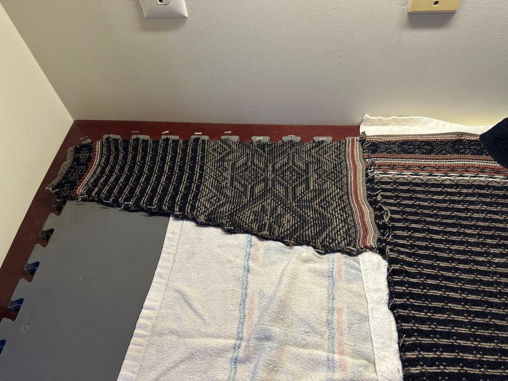 A photo of one sleeve of a Dale of Norway sweater. It has been pinned with "T" pins to hold its shape.