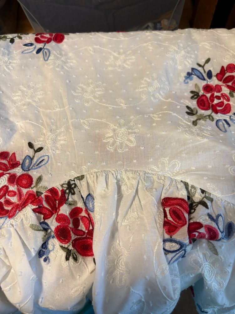 A close up of the fabric showing the embroidery and the curved seam with a ruffle gathered to it