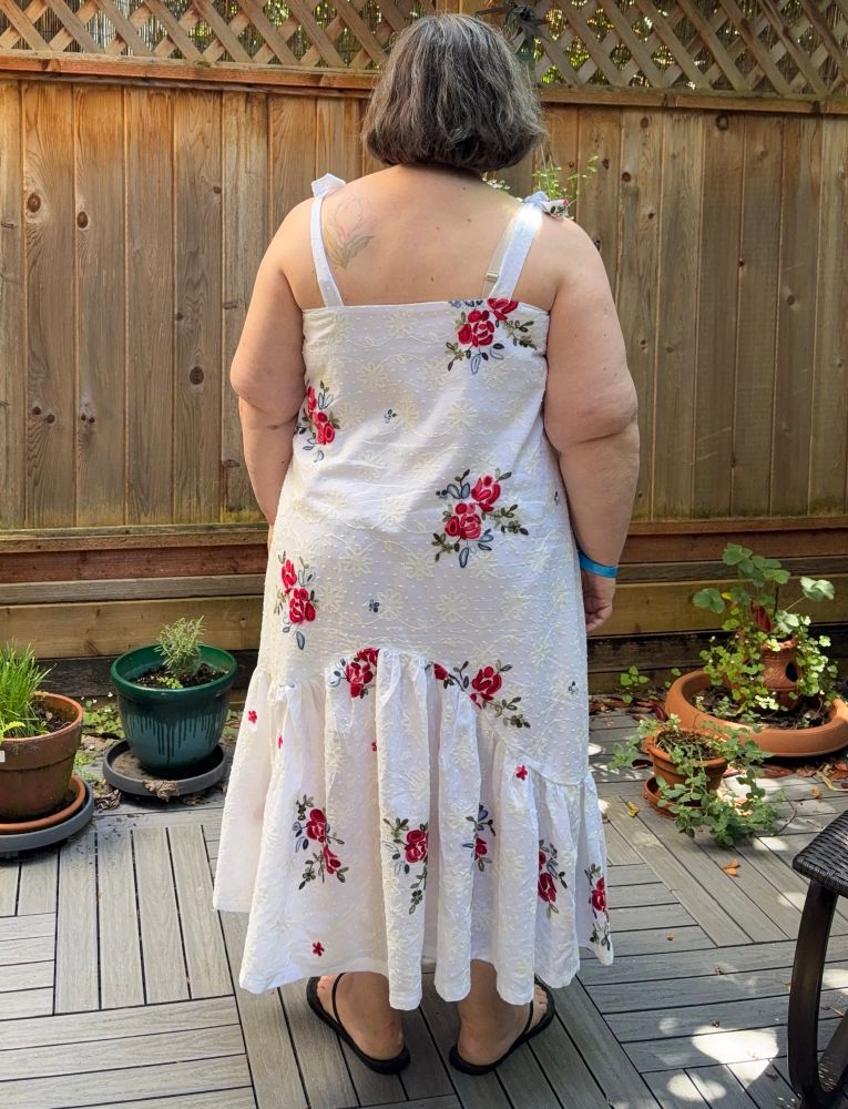 A back view of a woman in a white sundress with red flowers