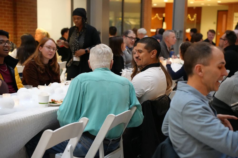 ISR colleagues gather around a long table decorated with candles and white ornaments during the 2025 Winter Party, enjoying food, conversation, and a festive atmosphere in the James S. Jackson Atrium.