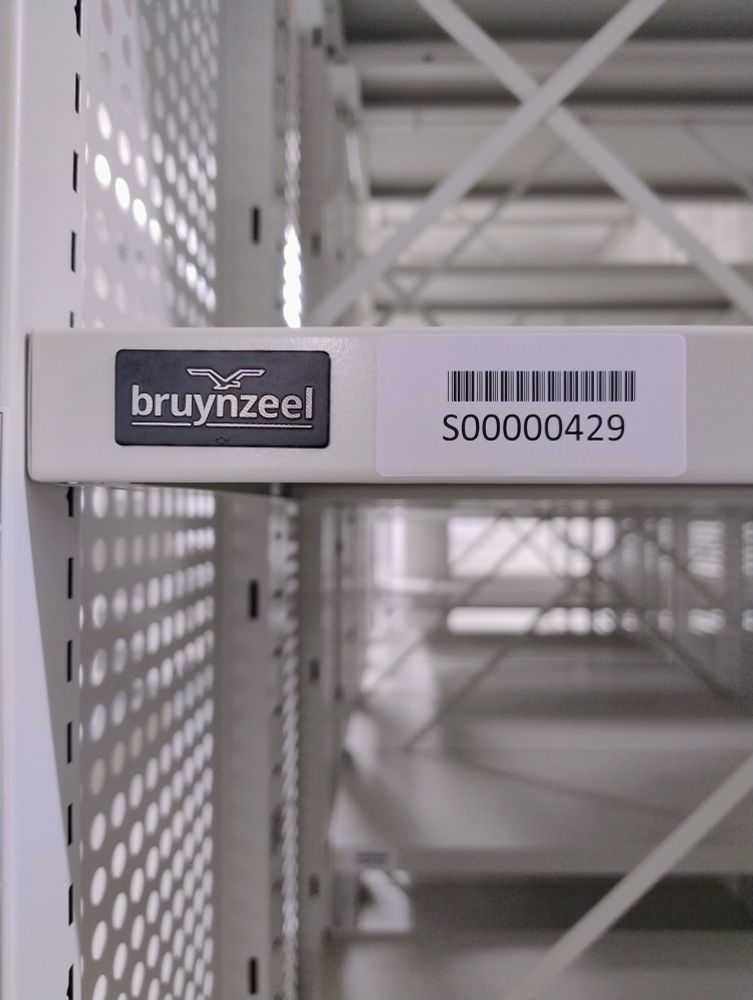 Shelf barcode next to a Bruynzeel product label on the new roller racking at Oldham Archives.