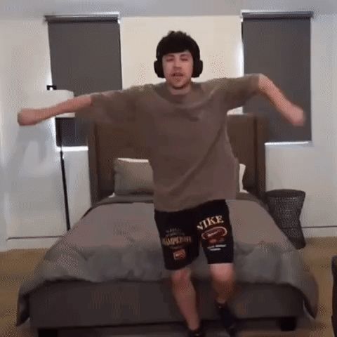 a man is dancing in front of a bed wearing nike shorts