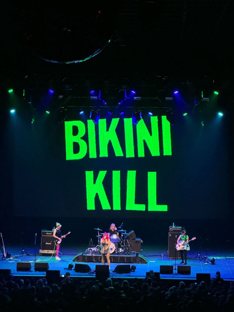 bikini kill! live! with a bikini kill sign behind them!
