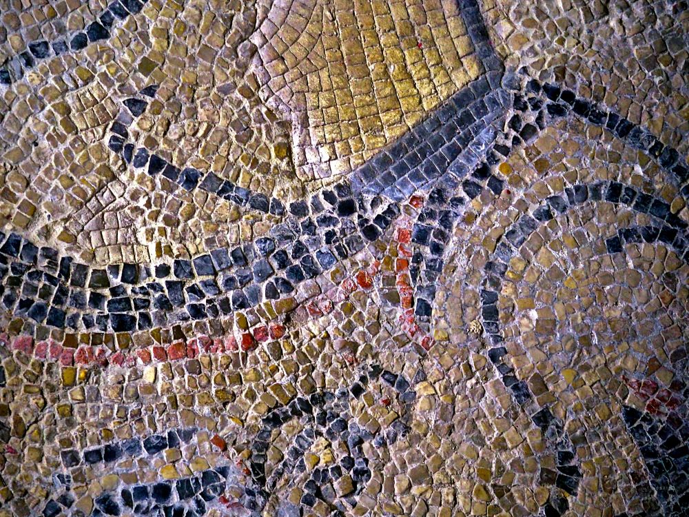 Mosaic flooring showing geometric shapes in black, red, yellow, and beige.