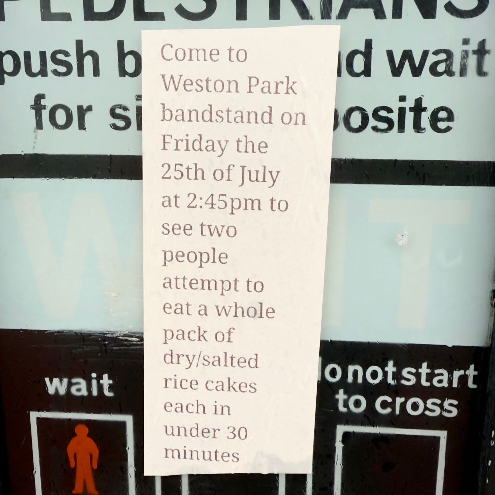 A paper flyer stuck to a pedestrian crossing. It says:
‘Come to Weston Park bandstand on Friday the 25th of July at 2:45pm to see two people attempt to eat a whole pack of dry/salted rice cakes each in under 30 minutes’