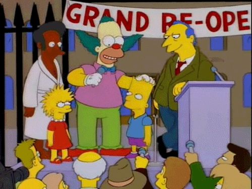 Krusty patting the head of Lester as Eliza and Apu and Roger Meyers Jr look on approvingly 