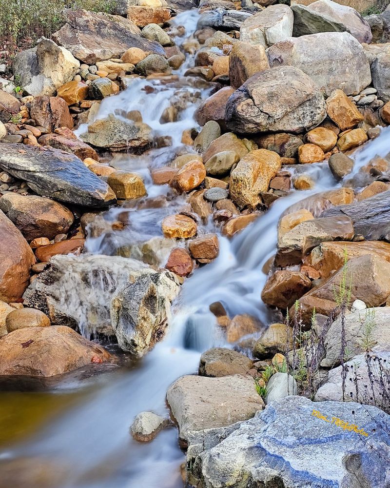 Assorted colors of rocks with water cascading down through them. 