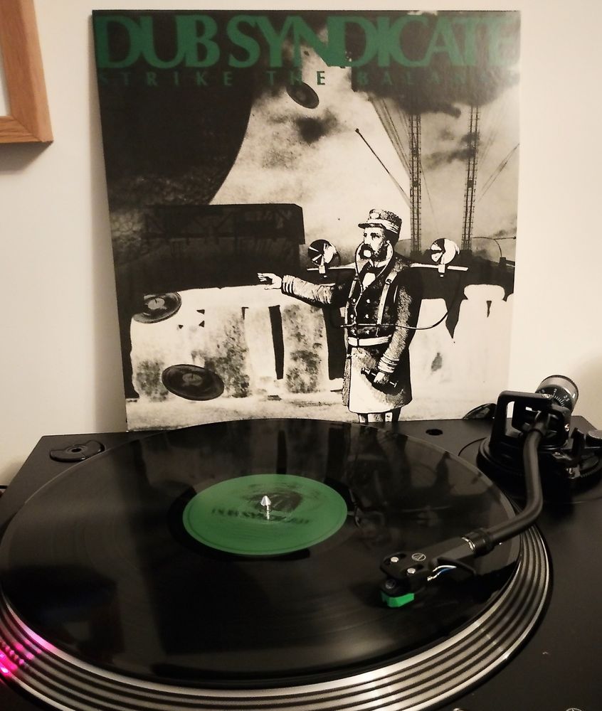 Black vinyl LP playing with album sleeve behind 