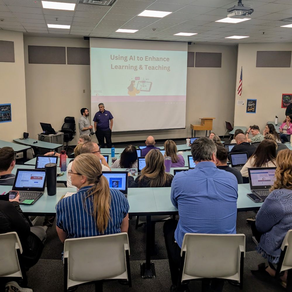 A room full of teachers on laptops facing a projector screen.