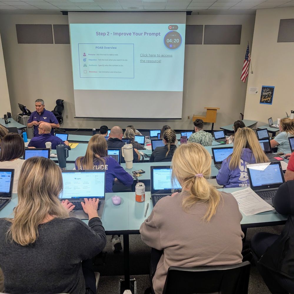 A room full of teachers on laptops facing a projector screen.