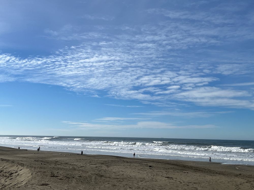 Image of white clouds against a blue sky above a beach. Ocean Beach, San Francisco