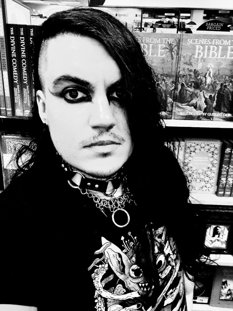 Goth guy in a book store with half shaved head and a collar.