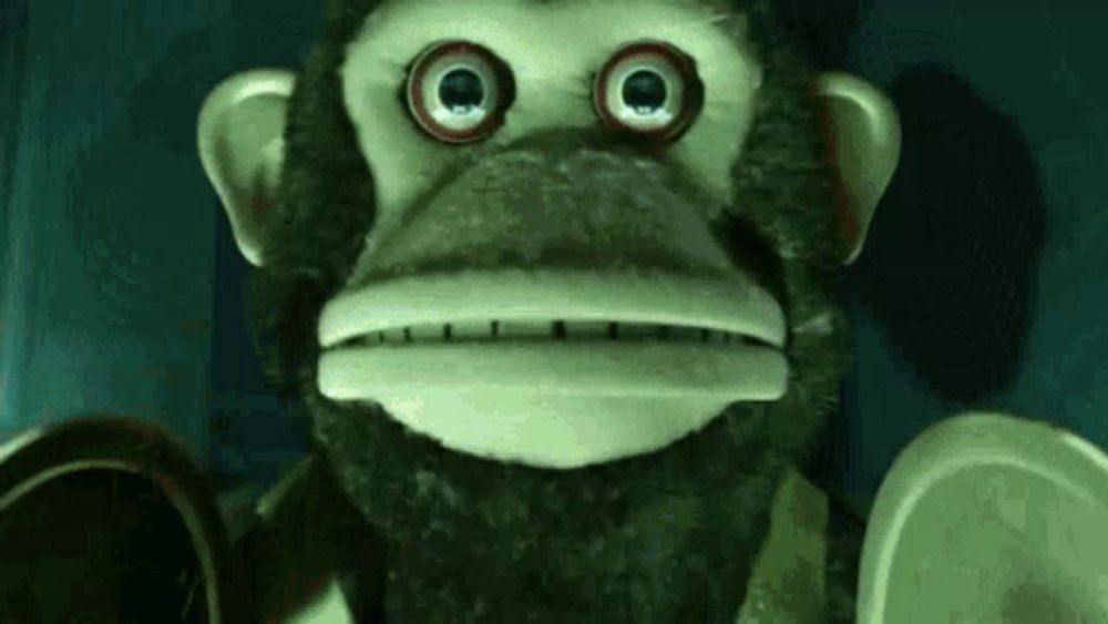 a stuffed monkey with big eyes and a beard is looking at the camera in a dark room .