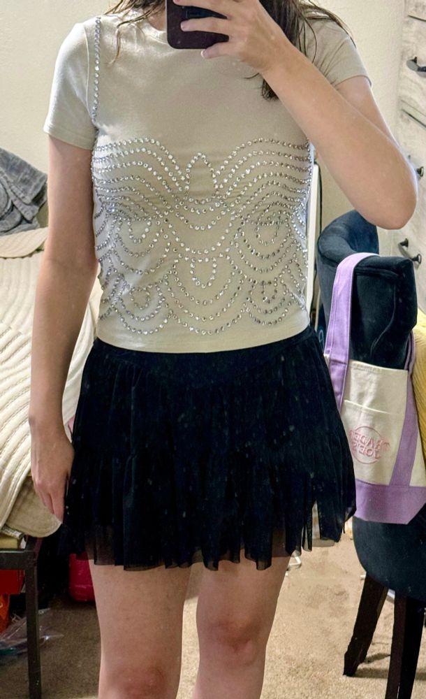 Photo of life of a showgirl premiere outfit: beige crop top bedazzled with rhinestones to look like Taylor’s album cover outfit and a black skirt