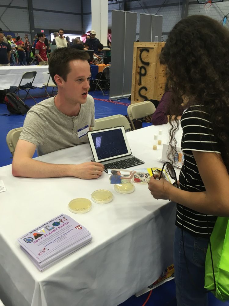 A scientist showing a middle school student E. coli. growing on afar plates