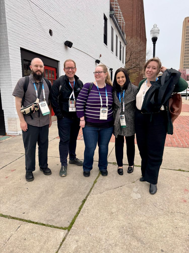a group of academics, wearing conference nametags, arrange themselves to stand together for a group photo (marisa posted the candid rather than the formal result)