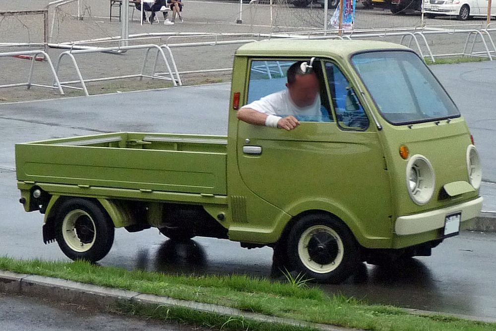 A green Mazda Porter kei truck. In this case the front air duct is open and resembles a nose.