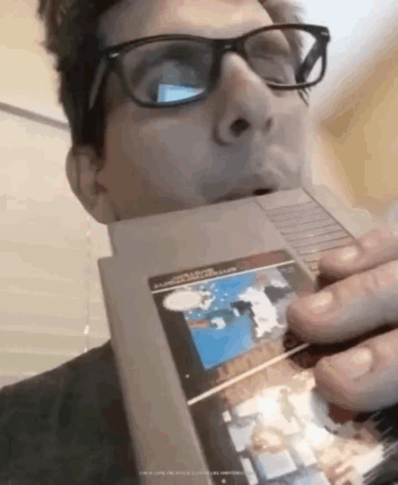 a man with glasses is biting into a video game