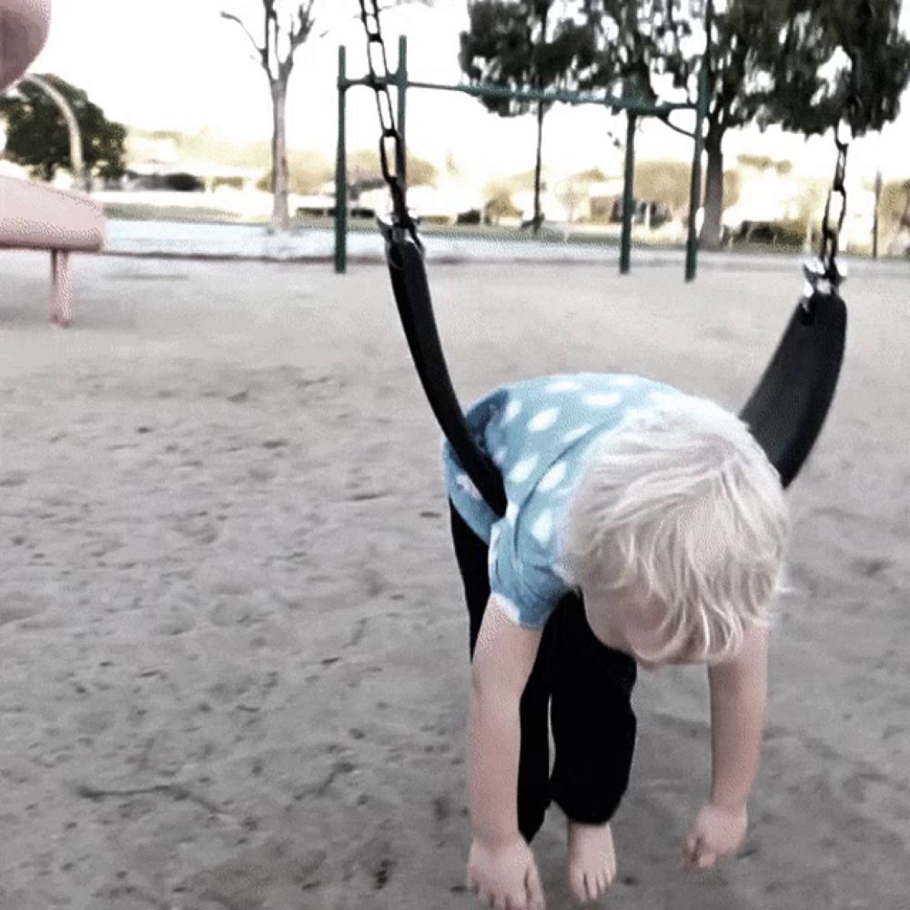 a young boy is playing on a swing in the sand