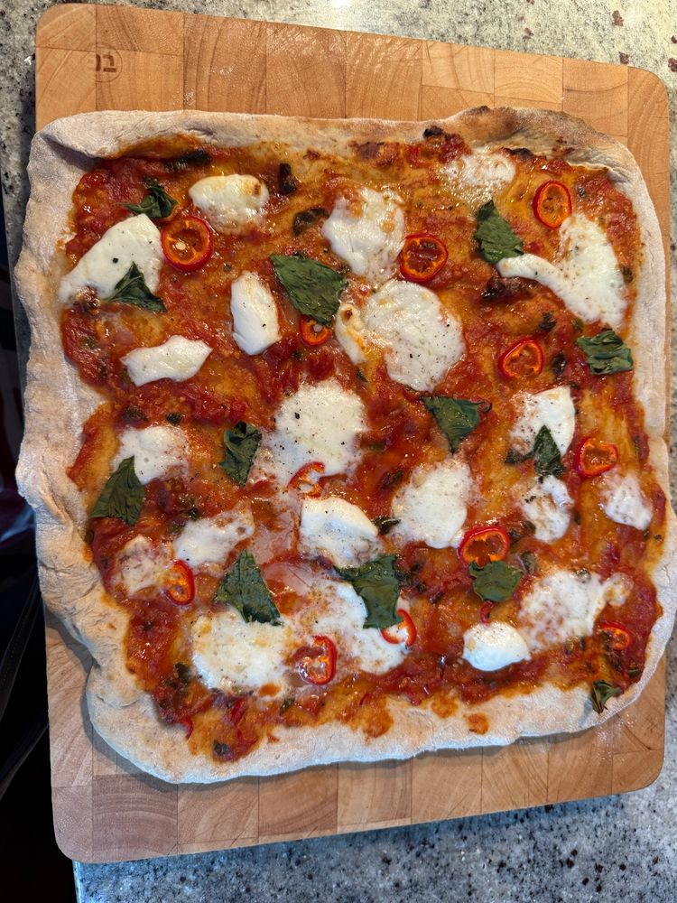 Homemade pizza with tomato sauce, buffalo mozzarella, chilli and basil 