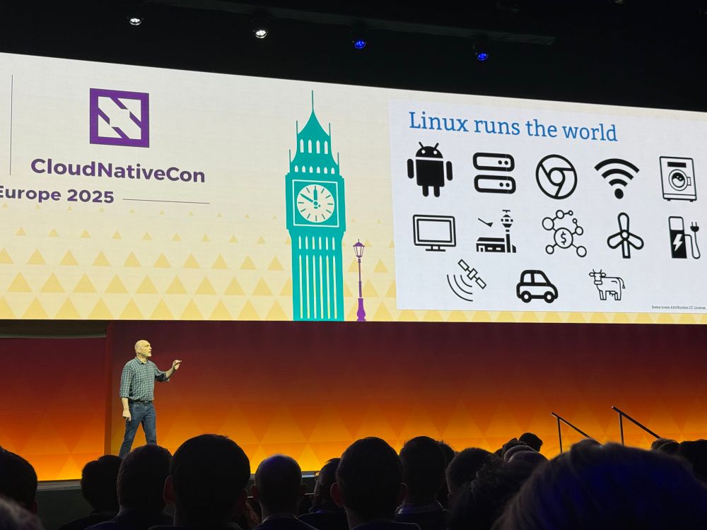 Greg on stage with a slide “Linux runs the world”