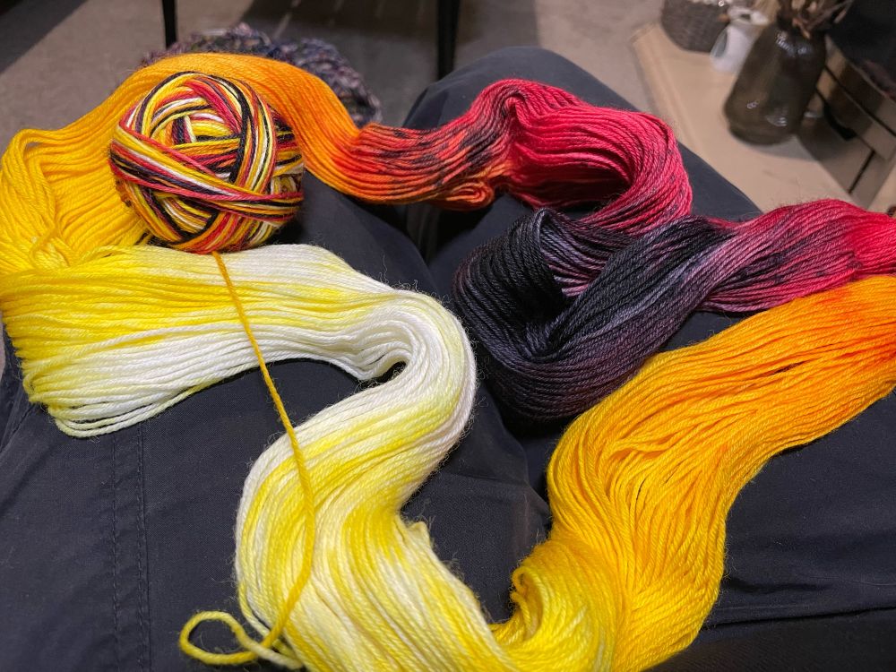 White, yellow, orange, and red yarn being wound into a ball. 