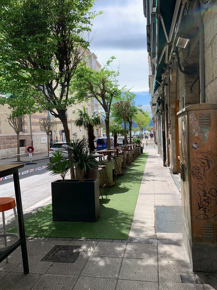 Terrazas hosteleras de Santander con césped artificial a modo de alfombra y arbolado de plástico. 