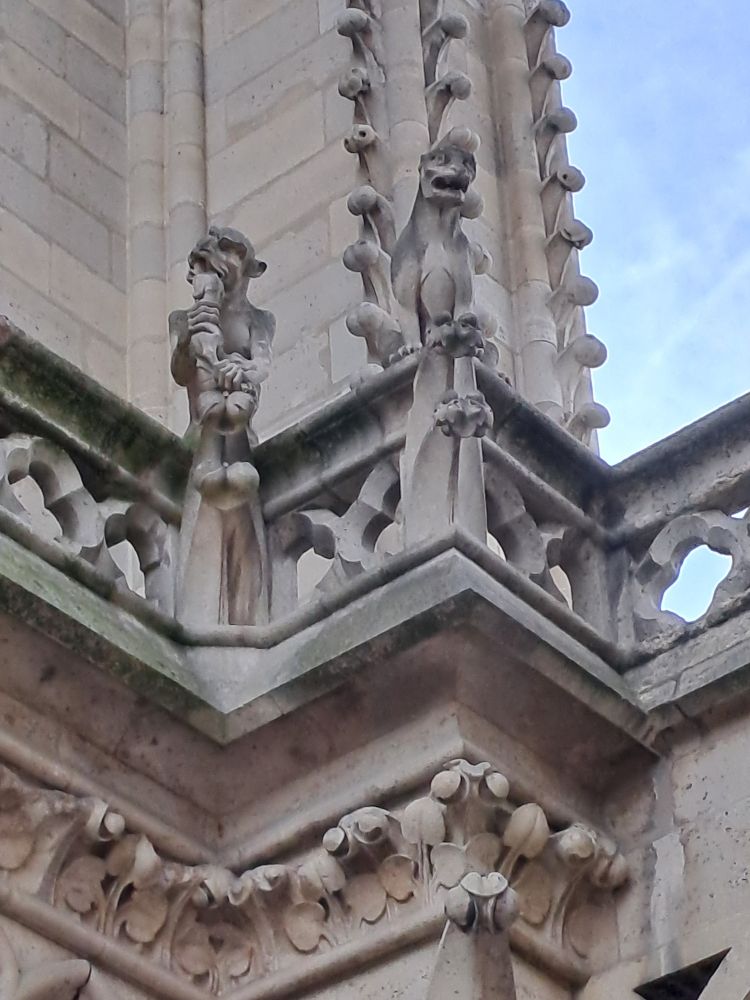 Two gargoyles with monkey-like features, perched on a railing outside.