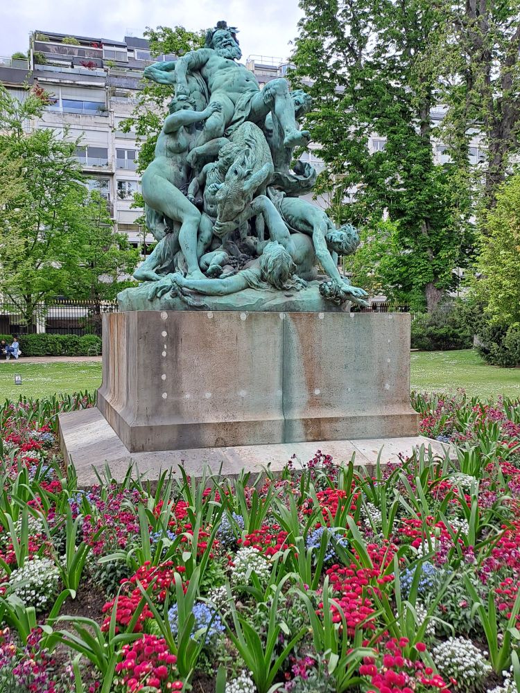 The sculpture "Le triomphe du Silène" by Aimé Jules Dalou  surrounded by a field of flowers at Jardin du Luxembourg.