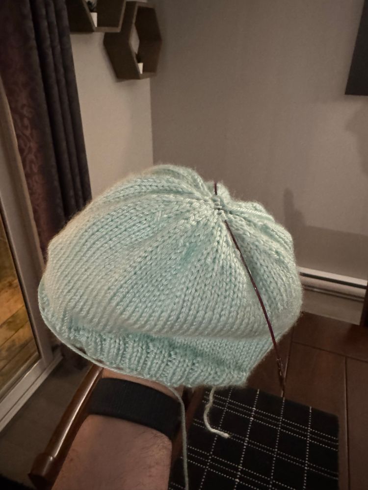 A teal beanie is held out for the camera. It’s not much to look at, but it’s a first attempt. 