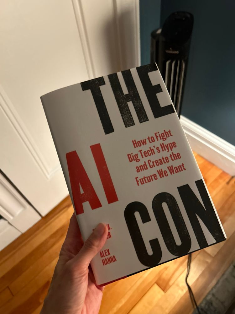 A copy in my hand of The AI Con by Emily Bender and Alex Hanna