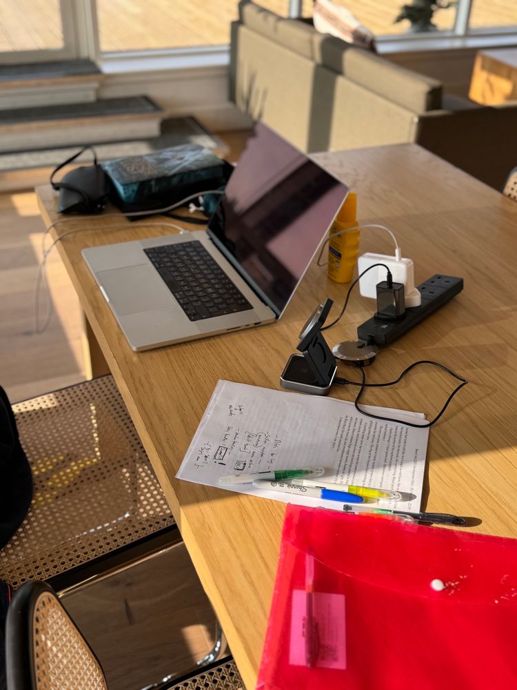 Laptop on a desk, notes beside it and a red envelope. 