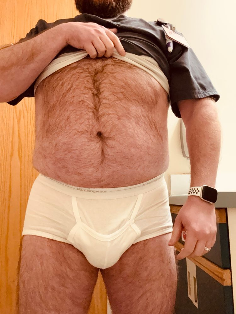 A thigh-to-chin photo of me in a pair of white Munsingwear pouch briefs. The heavy package between my hairy thighs strains the pouch, so that the horizontal fly sags in the middle.