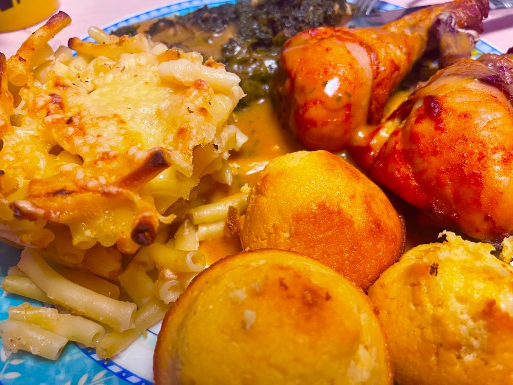 Baked Mac’n’cheese, turkey legs, greens, gravy and cornbread cupcakes on a blue floral plate