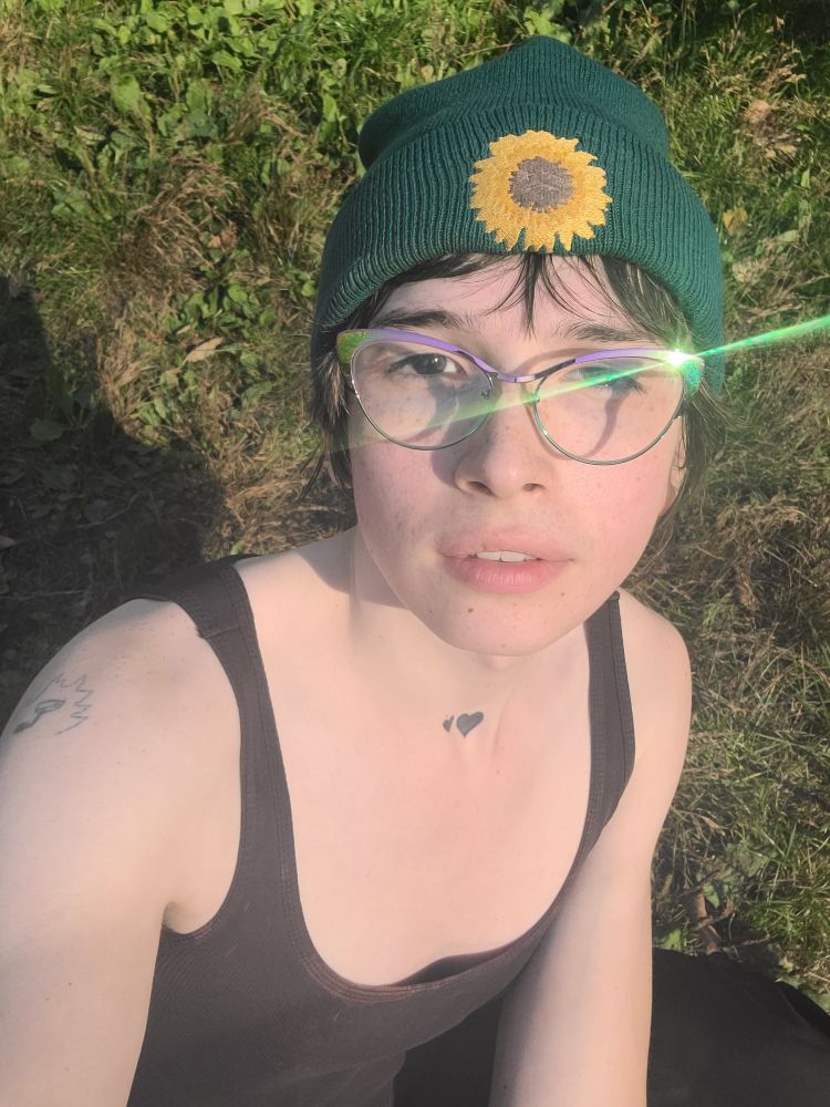 xae glimmering in the sun wearing a tank top and beanie