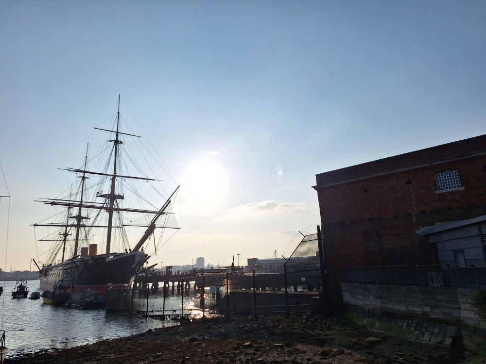 Image shows HMS Warrior with the sun shining behind it
