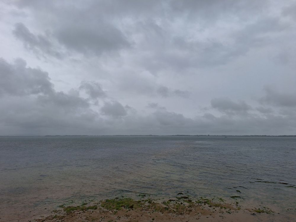 Image shows Langstone harbour at high tide under a cloudy sky 