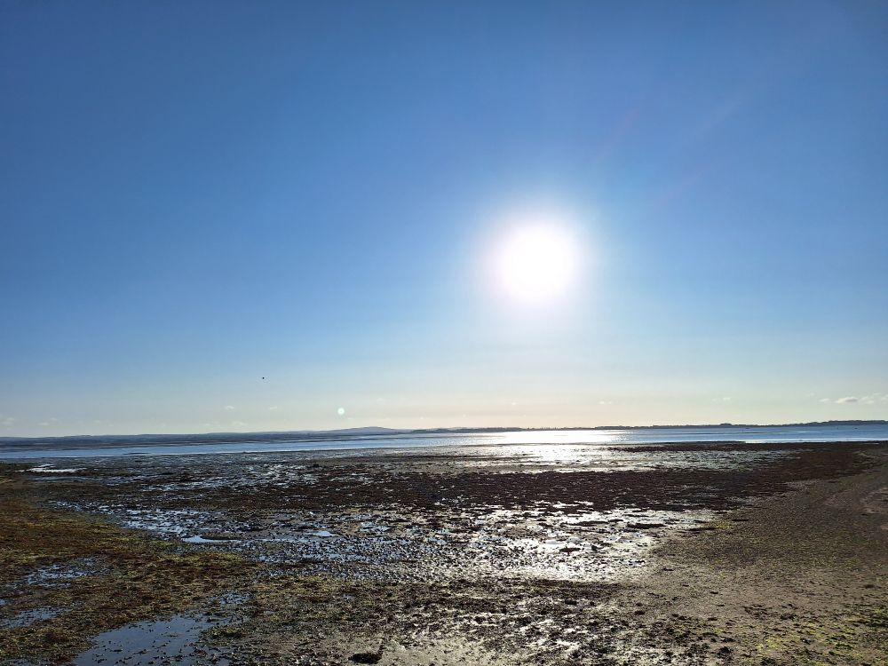 Image shows Langstone harbour at near low tide under a clear, sunny sky 