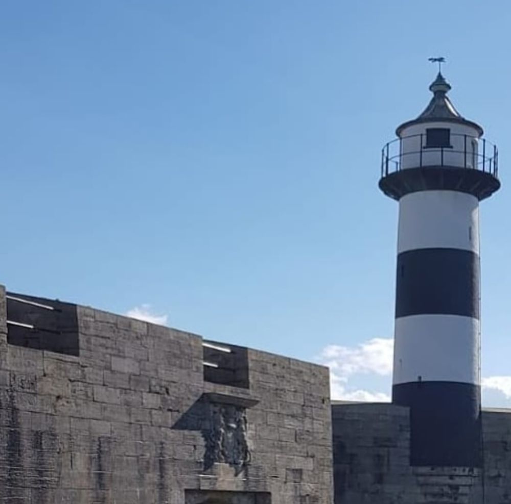 Image shows Souhsea Castle and lighthouse under a clear sky 